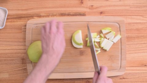Cutting green apple in slices on wood board top view