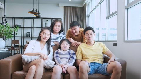 Excited big asian multi age family cheering in front of tv. big happy family watching sport match on tv movies feeling excited and thrilled on sofa in living room home interior background