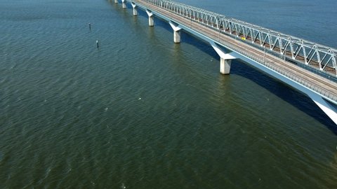 Aerial day time sunny weather shot of Dutch modern passenger train crossing train bridge over Hollands Diep, Netherlands