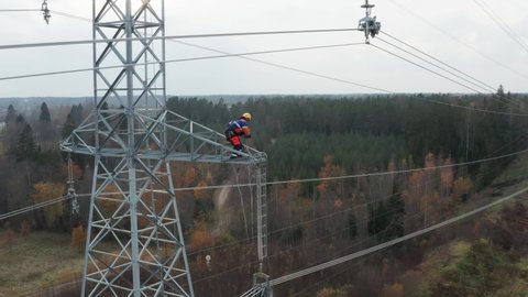 Engineer working high up on pylon, hoisting equipment up.
