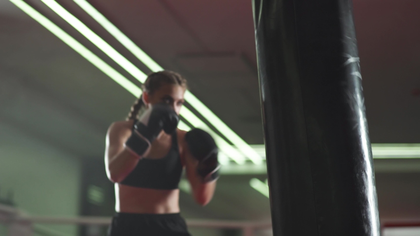 Boxing, woman fighter trains his punches, beats a punching bag, training day in the boxing gym, strength fit body, the girl strikes fast. Royalty-Free Stock Footage #1058808802