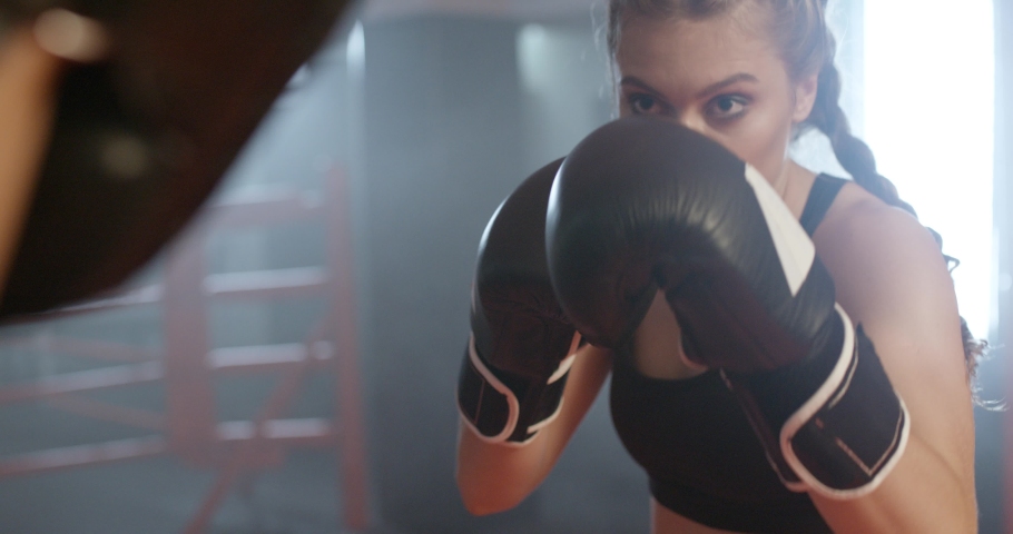 Cinematic shoot of boxing in the ring, woman fighter trains punches and punching focus mitts, training day with trainer in the boxing gym, 4k slow motion. Royalty-Free Stock Footage #1058808805