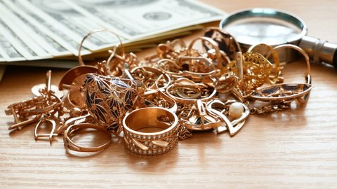 jewelry scrap of gold and silver and money, magnifying glass on wooden background, pawnshop concept