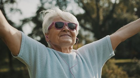 Senior retired woman enjoying the freedom of retirement. Outstretched hands in the park, close up. High quality 4k footage