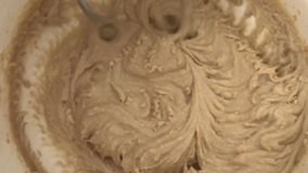 Beating sugar and butter with mixer in a bowl, video top view and closeup