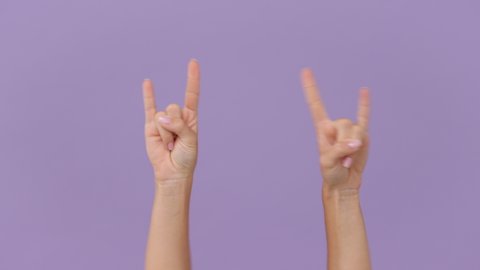 Close up cropped woman hands depicting heavy metal rock sign horns up gesture fooling rock-n-roll isolated on pastel purple violet background in studio. Copy space advertising area workspace mock up