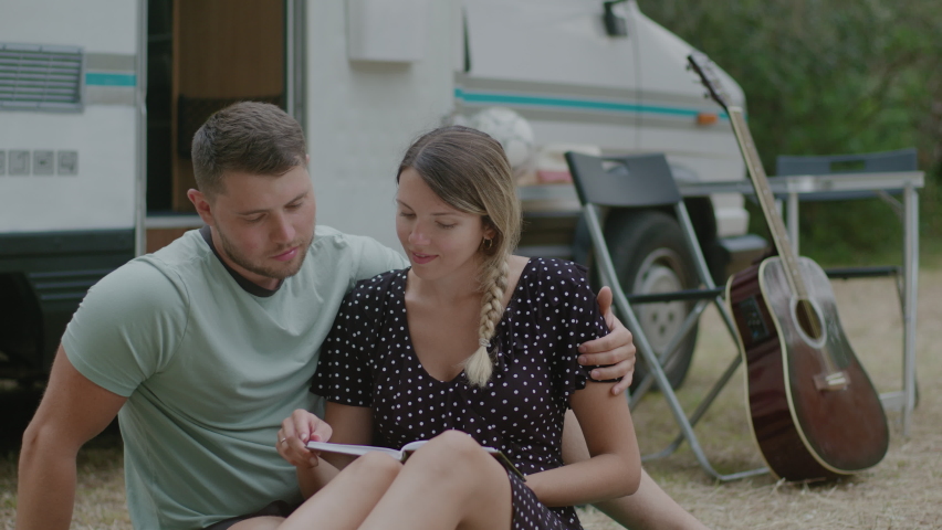 Lovely couple sitting together and reading a book against motor home RV campervan. Man and woman enjoyng vacation in road trip.
 | Shutterstock HD Video #1058817763