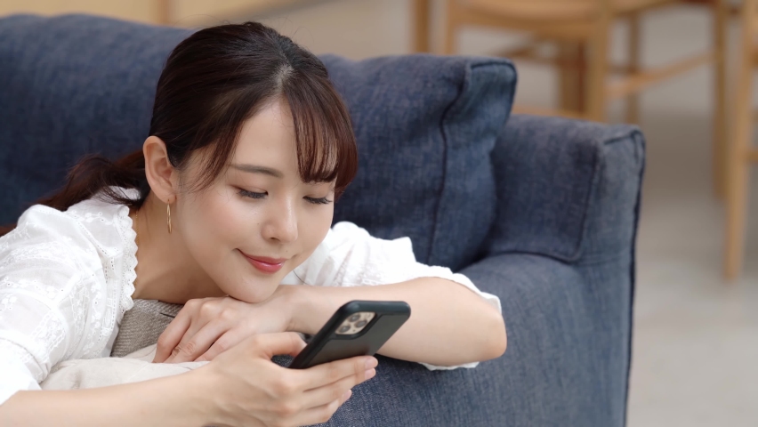 Young asian woman using a smart phone in the room. Royalty-Free Stock Footage #1058820424