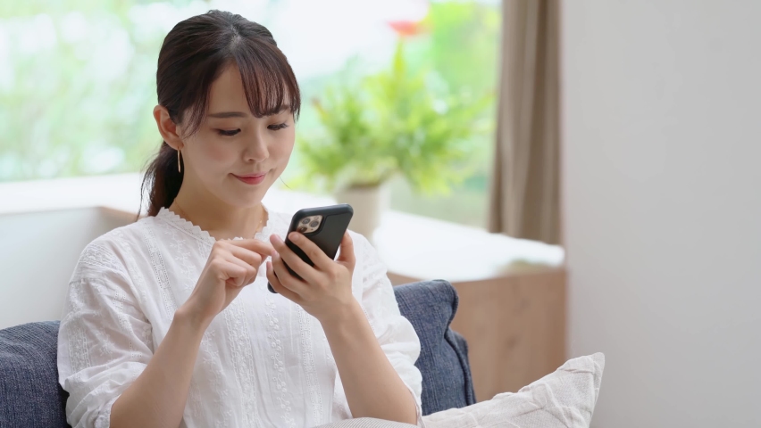 Young asian woman using a smart phone in the room. Royalty-Free Stock Footage #1058820430