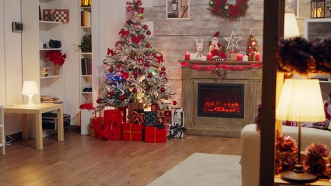 Stylish room interior with christmas tree and gift boxes with fireplace burning.