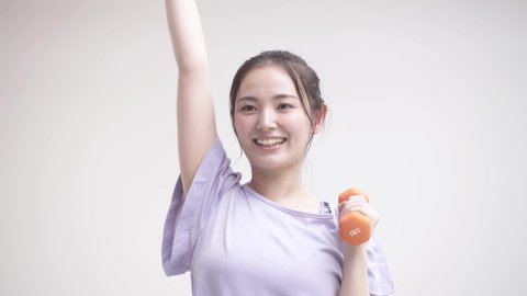 Young woman doing muscle training with dumbbells