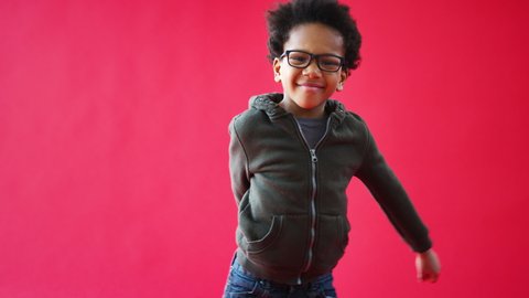 Young Boy Wearing Glasses Dancing Flossing Against Red Studio Background Smiling And Laughing