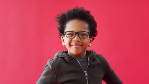 Young Boy Wearing Glasses Dancing Against Red Studio Background Smiling And Laughing