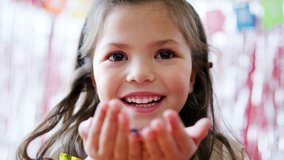 Girl In Party Hat Celebrating At Birthday Party Blowing Handful Of Gold Confetti And Glitter - Powered by Shutterstock - Get 15% off with code: PIKWIZARD15