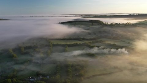 Aerial clip of rolling Devon countryside in dawn mist, Brentor, Devon, England, United Kingdom, Europe