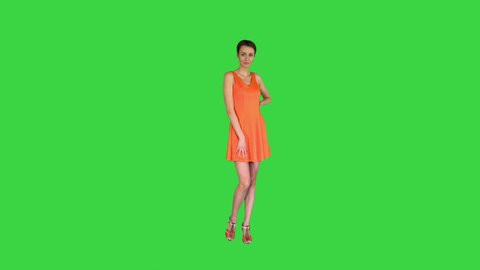 A beautiful, cheerful woman straightens her dress on a Green Screen, Chroma Key.