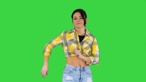 Girl in square shirt and jeans shorts, sneakers, dancing on a Green Screen, Chroma Key.