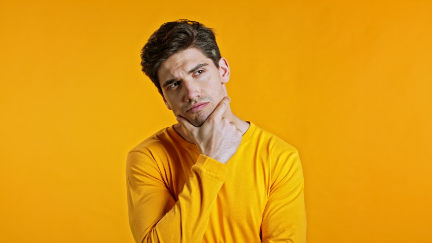 Thinking man looking up and around on yellow background. Worried contemplative face expressions. Handsome male model. Royalty-Free Stock Footage #1058826943