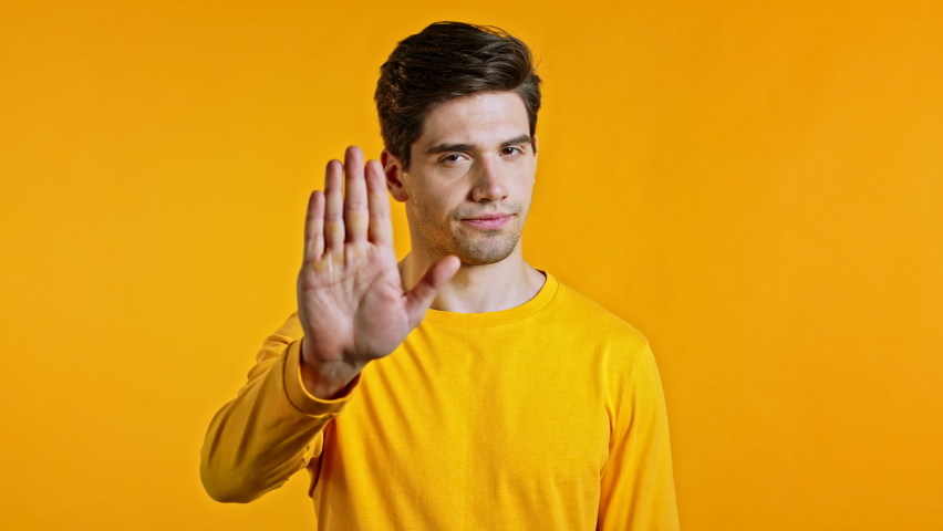Man disapproving with NO hand sign gesture. Denying, rejecting, disagree, a portrait of a man on a yellow background. | Shutterstock HD Video #1058826964