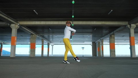 Contemporary street dancer in yellow pants is dancing freestyle in the city. Classical dance or ballet.