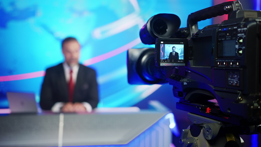 Professional TV Camera Standing in Live News Studio with Anchor seen in Small Display. Unfocused TV Broadcasting Channel with Presenter, Newscaster Talking. Mock-up Television Channel Newsroom Set Royalty-Free Stock Footage #1058828704