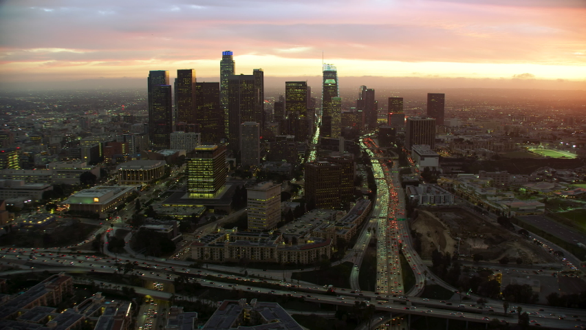 Amazing aerial view of downtown Los Angeles. City skyline with its famous skyscrapers over a colorful sky. Traffic over major highways. California, United States. Shot on Red Weapon 8K.