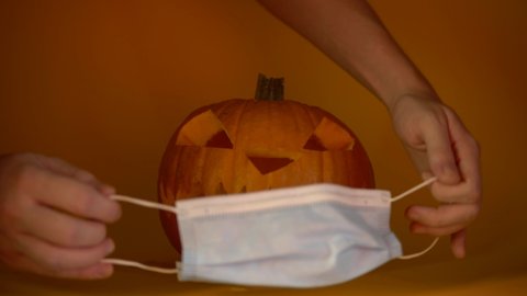 Halloween carved glowing pumpkin with medical mask, put protective mask on quarantine, coronavirus halloween 2020