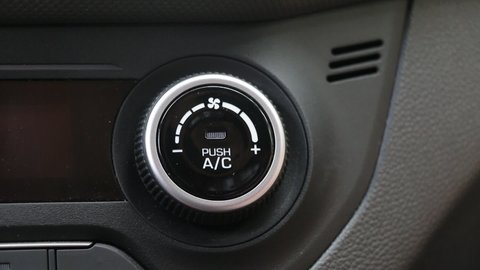 Hand adjusts the air conditioner control button in the car