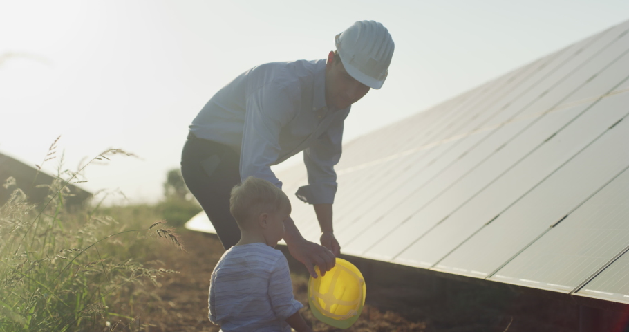 An young engineer father is explaining to his little son an operation and performance of photovoltaic solar panels at sunset. Concept:renewable energy, technology, electricity, green,future, family,  Royalty-Free Stock Footage #1058850190
