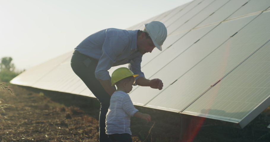 An young engineer father is explaining to his little son an operation and performance of photovoltaic solar panels at sunset. Concept:renewable energy, technology, electricity, green,future, family,  | Shutterstock HD Video #1058850190