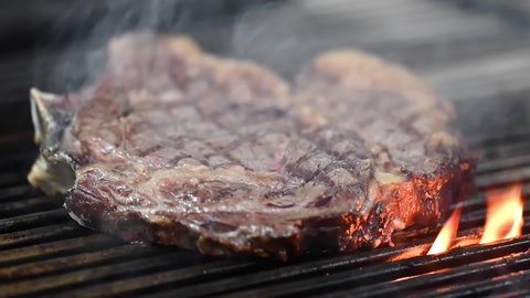 Close up of delicious beef steak on flaming grill. High quality FullHD footage