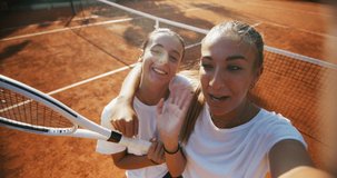 Authentic shot of young happy teenage tennis players friends having fun to make selfie or video call to friends or family after a friendly match or training workout game on the court in a sunny day.