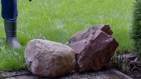 A male gardener washes decorative stones from dirt and moss using a high pressure washer. Splashes of water scatter in different directions. Home Garden Care. Gardener or cleaner job concept.