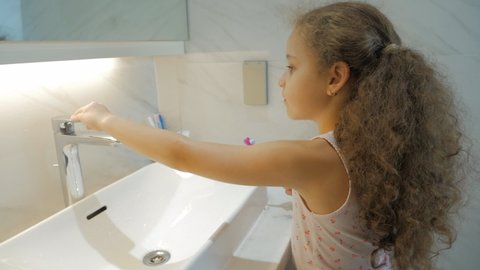 Happy portrait cute caucasian young teenage girl brushing teeth in bathroom. Child daily healthcare routine. Kid with white tooth looking at mirror isolated at home. Smiling Lifestyle.