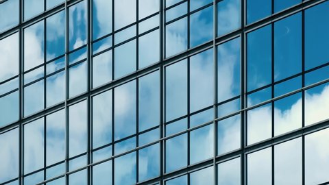 Time lapse of blue sky and clouds reflected in structural modular glass wall. 
