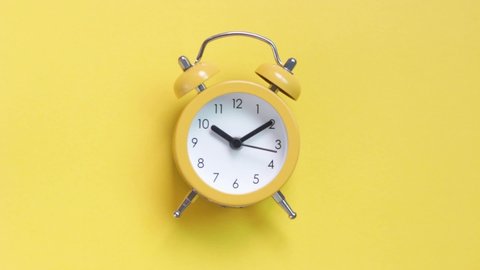 Yellow alarm clock on a yellow background close-up, top view