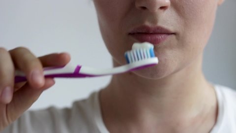 The girl brushes her teeth with a toothbrush with paste close-up.