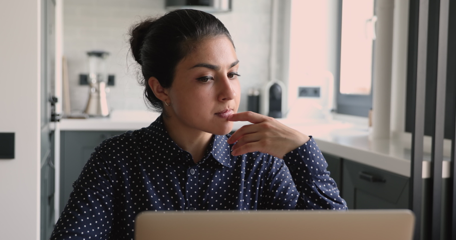 Young indian woman sit in homeoffice working on laptop doing remote freelance tasks looking pensive or concerned, thinking of problems, solving business issues. Creative telework, brainwork concept | Shutterstock HD Video #1058862400