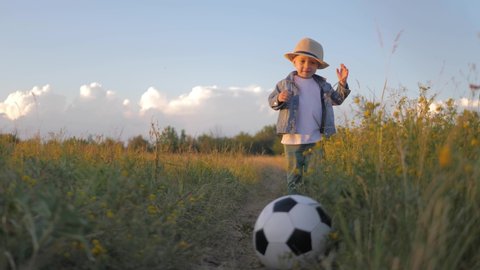 Little boy kicking a soccer ball at sunset. Child dreams of becoming a soccer players.