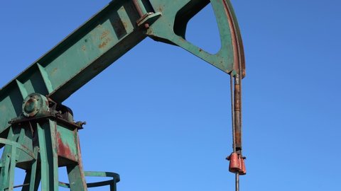 Oil Field Pump Jack Against Blue Sky. Petroleum Industry Pump Jack Extracting Crude Oil from a Oil Well. Fossil Fuel Energy. Oil Industry Equipment.