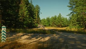 Cinematic clip of a buggy car is driving in cross country road. Buggy is driving with big clouds of dust. Racing off-road car in the forest road.   