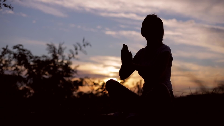 Silhouette of a woman praying with Amazing dramatic sky sunset background. Royalty-Free Stock Footage #1058864419