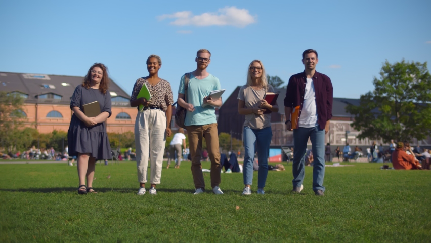 Group of diverse college students spending time together on campus at university yard. Happy multiethnic friends walking in city park going on lecture in university Royalty-Free Stock Footage #1058873554
