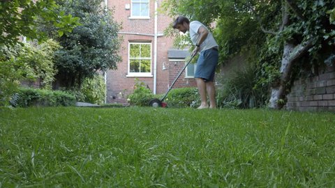 A man mows the lawn with a manual push mower