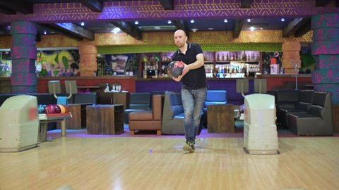 Bald man throws a ball while bowling