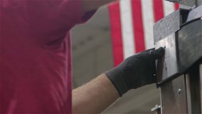 Patriotic USA American Blue Collar Essential Worker Drills into metal with American Flag in rafters in Backdrop. Strong biceps, American Jobs, patriotism.  - Powered by Shutterstock - Get 15% off with code: PIKWIZARD15
