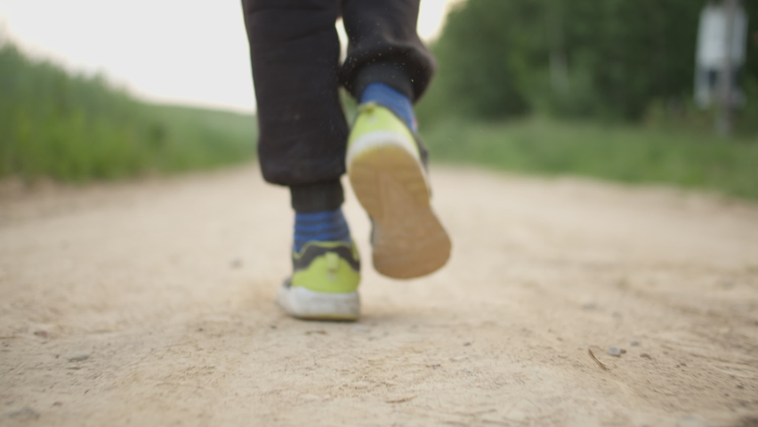 close-up of a boy's feet walking along a country road in dirty clothes Royalty-Free Stock Footage #1058892958