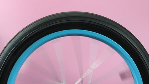 bicycle wheel with shining metal spokes spinning against a pink background, advertising backdrop with copy space