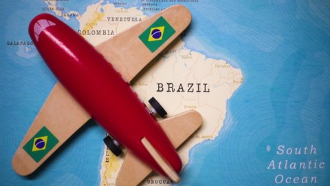 A red plane with a flag of Brazil attached to its wings is crossing the map of Brazil.