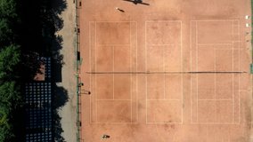 Tennis clay court seen from above with two men playing match. They are mature adult, and very agile and healthy. Video made with drone